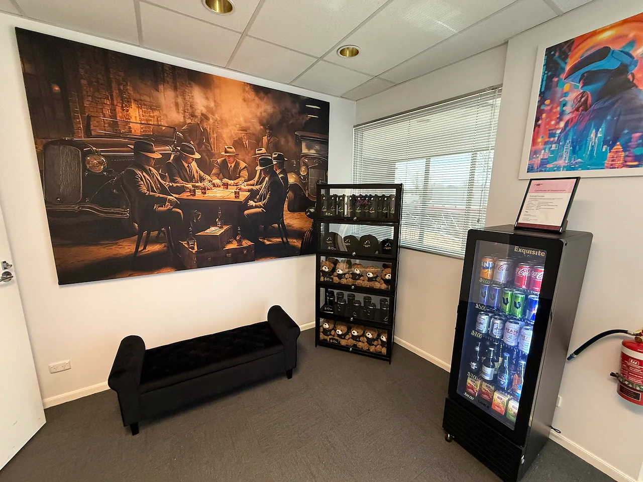 The venue arrival area with bench seating, wall artwork, shelving and a drinks refrigerator.