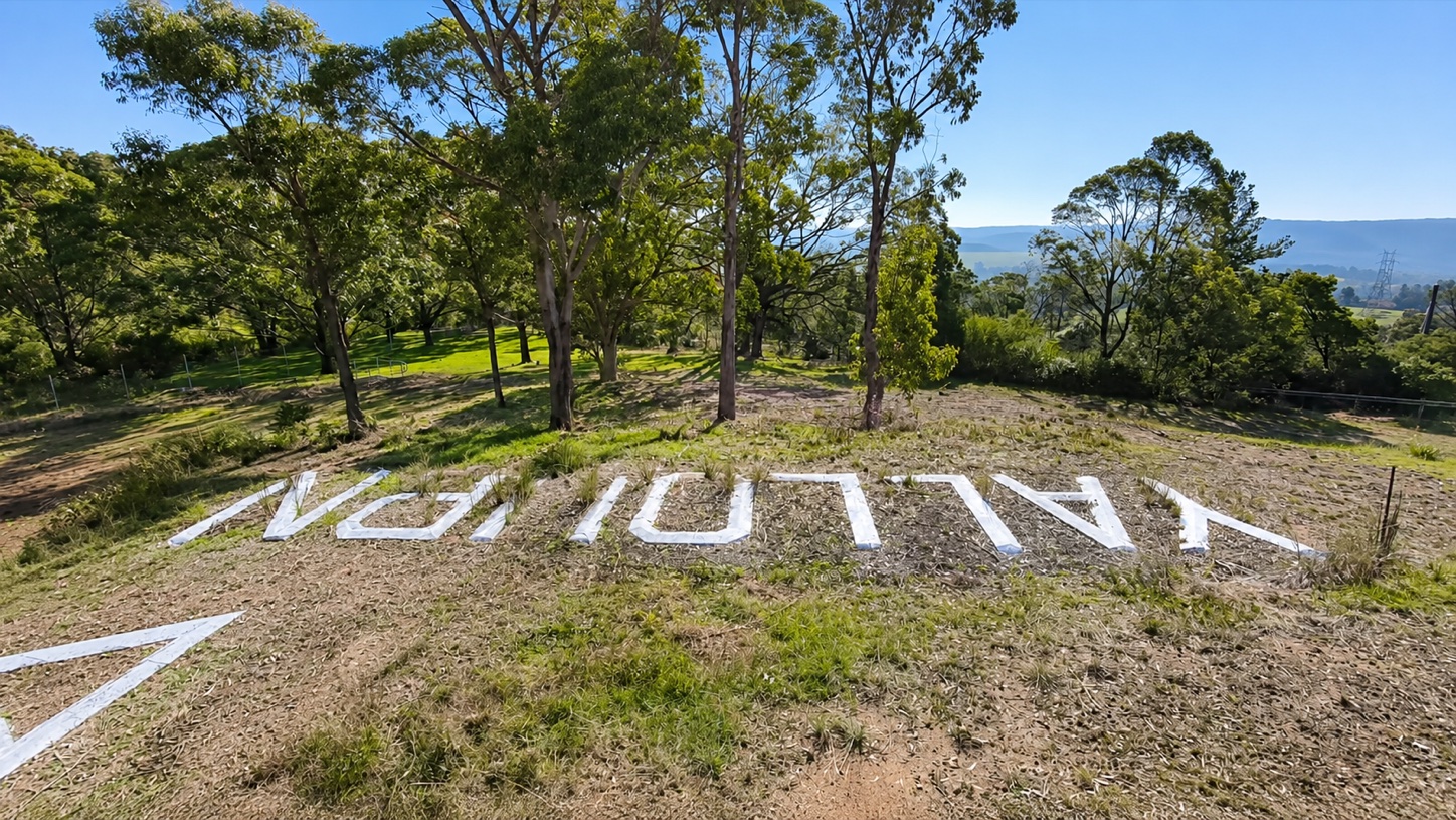 The concrete YALLOURN letters of the aerial navigation marker seen across the hillside among trees in 2026.