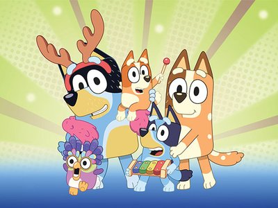 A colourful stage production featuring large-scale puppet versions of Bluey and Bingo from the animated TV series, performing before a live theatre audience.