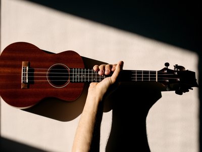 A small group of smiling adults holding ukuleles during a beginner music lesson in a relaxed indoor setting.