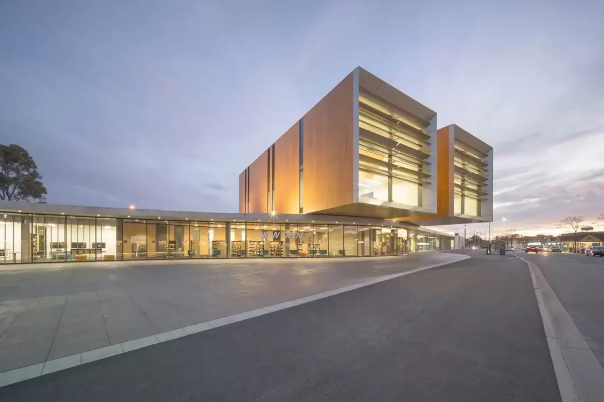 The illuminated Frank Bartlett Memorial Library and Moe Service Centre beside the street at dusk.