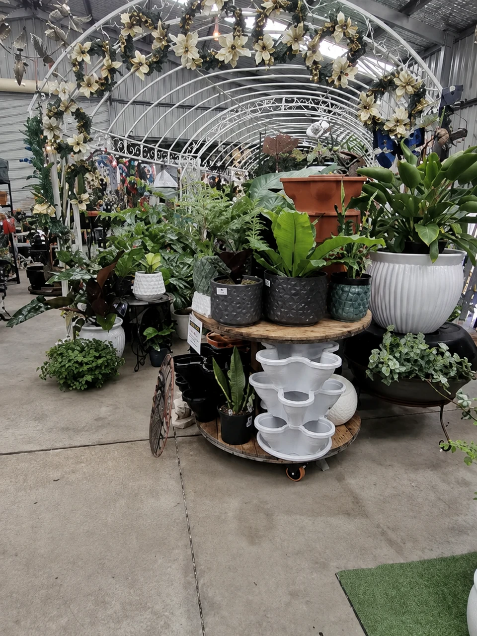 Plants and pots arranged along a central aisle inside Traralgon West Nursery.