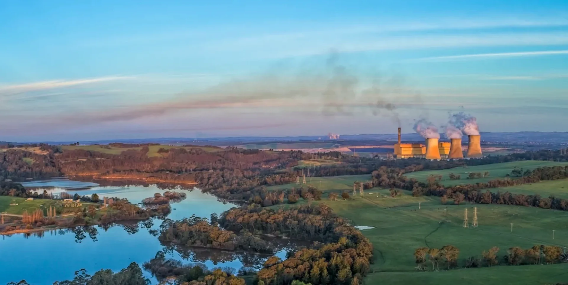 Wide view across farmland and water towards Yallourn Power Station and its cooling towers.