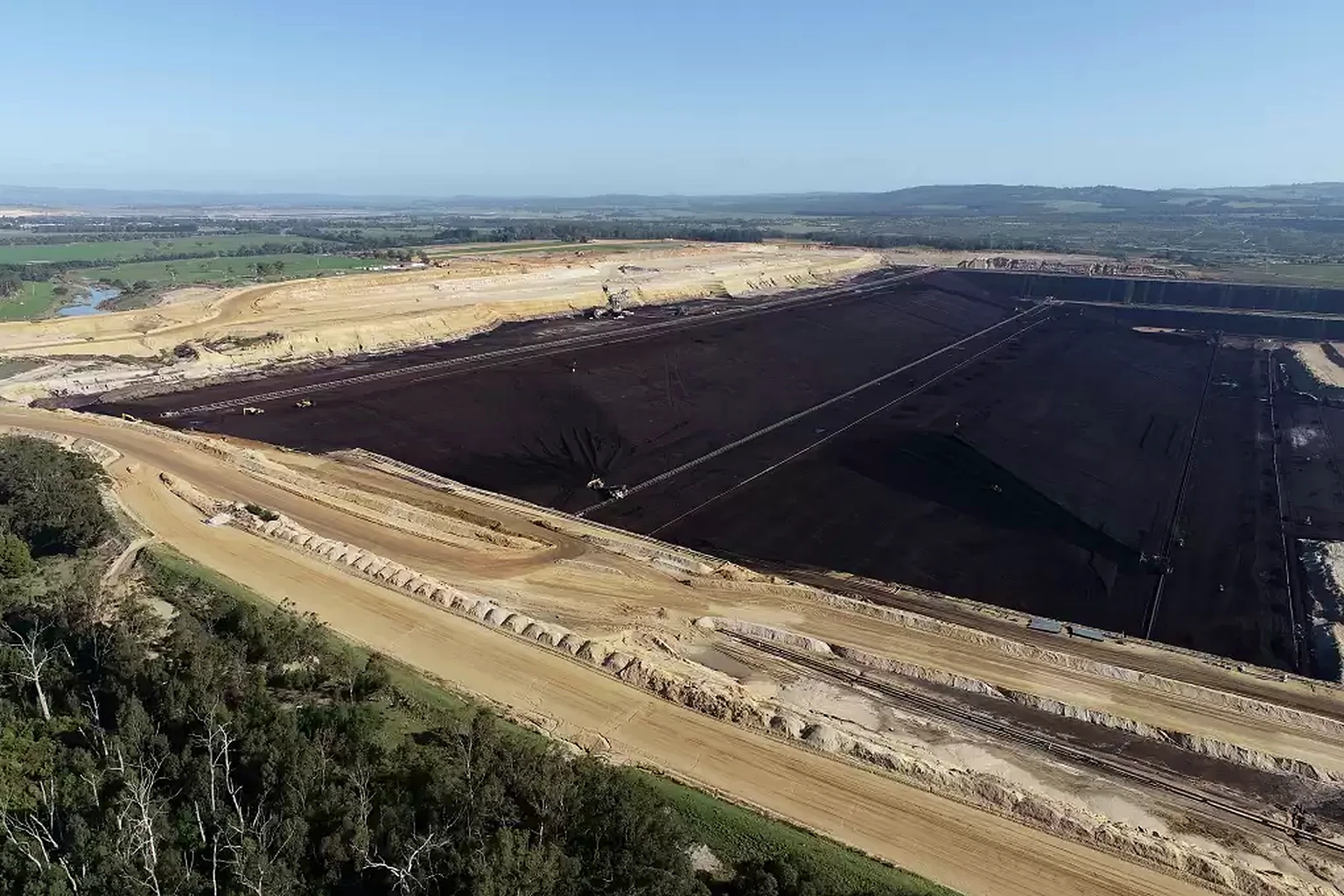 Terraced brown-coal mine with haul roads and conveyor infrastructure.