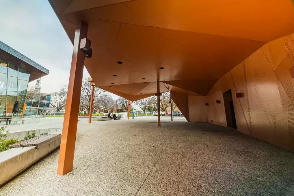 A folded copper-coloured canopy shelters the open forecourt beside Traralgon Library.