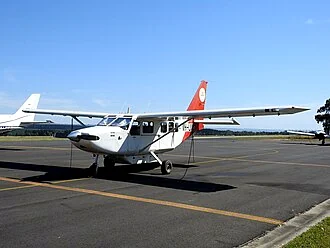 A white twin-engined light aircraft parked on an airport apron.